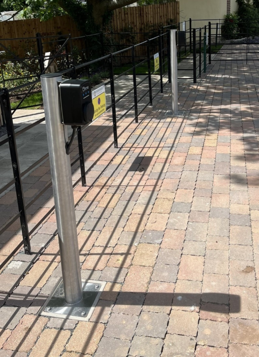 Outdoor EV charging station with mounted chargers on metal posts along a paved area, ready for vehicle charging.